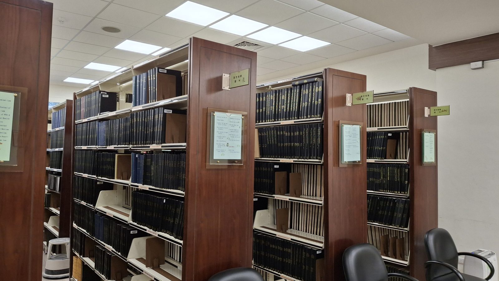 Rader av höga bokhyllor fyllda med böcker i ett bibliotek