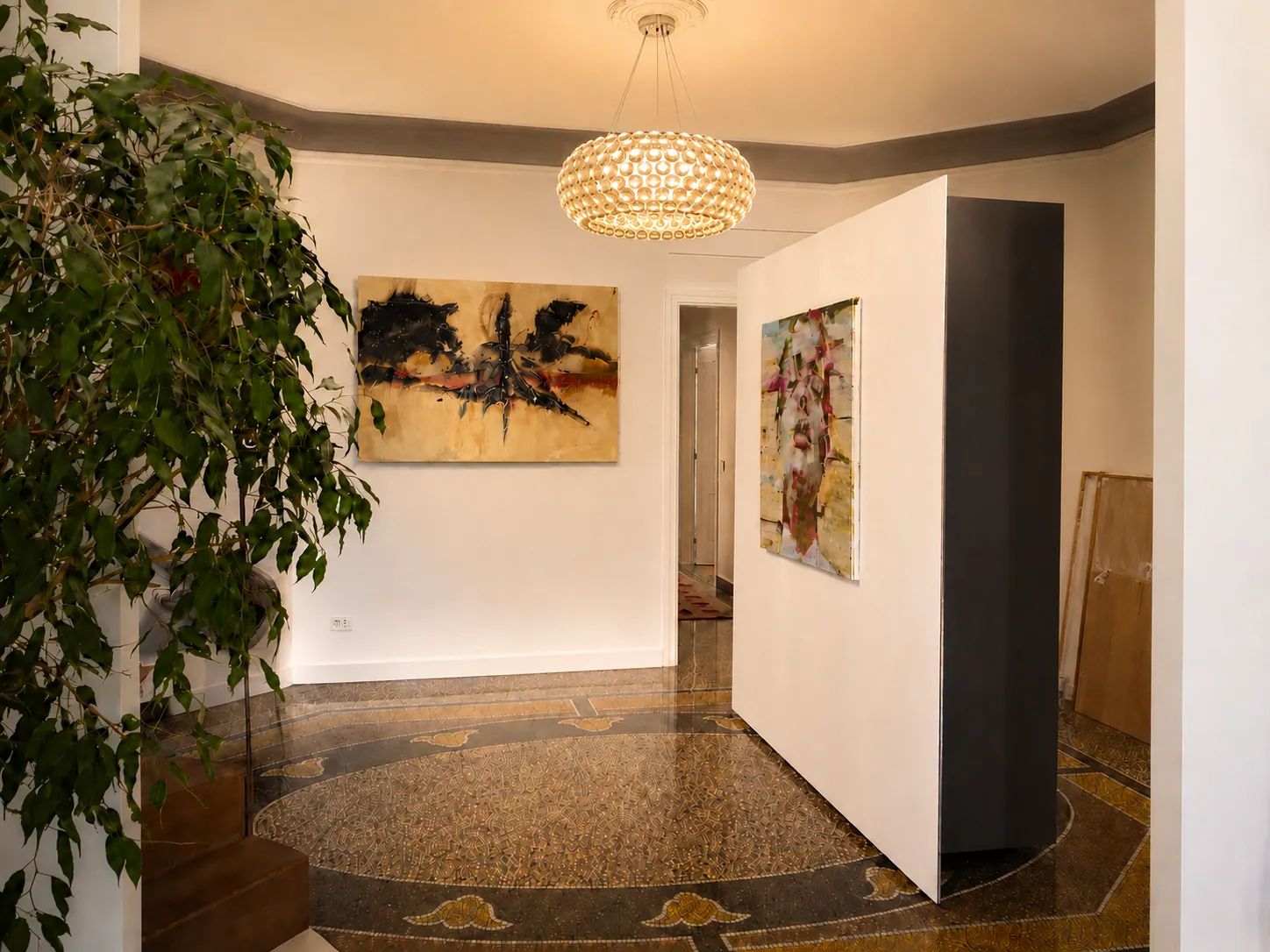 Ingresso di appartamento storico a Genova con pavimento decorato, opere d’arte contemporanea e lampadario Caboche Foscarini.